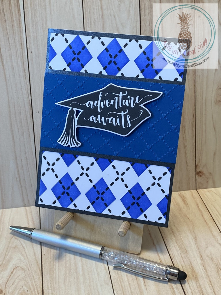 Blended argyle background in blue and black mounted on a black shimmer paper card panel. A large graduation cap silhouette with the sentiment "adventure awaits" is popped up on a blue cardstock strip that is embossed with an argyle pattern and the blue strip is then attached to a black shimmer paper strip. Internal sentiment reads "here's to a bright future". A2 card size: 4.25 x 5.5". Coordinating envelope included.