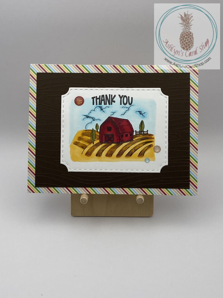 A thank you card with a farm theme. Hand coloured barn scene on brown cardstock and an additional layer of patterned paper (striped shown). A2 size card 4.25 x 5.5". Coordinating envelope included.
