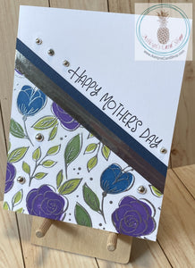A simple one layer card with a stamped and embossed floral design on the bottom left. Coloured cardstock and a metallic stripe complement the floral design. Metallic bubbles are added as an accent. External sentiment reads "Happy Mother's Day" and the internal sentiment reads "I am a strong woman because I was raised by a strong woman." Blue & silver version. Card size is A2 (4.5 x 5.5"). Coordinating envelope included.