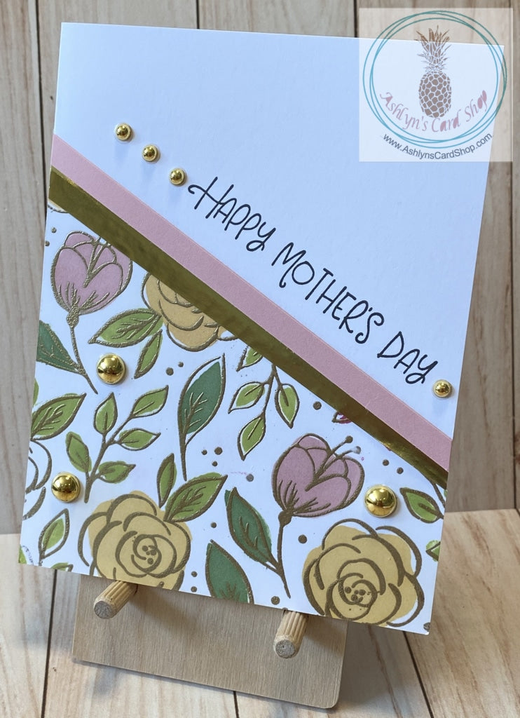 A simple one layer card with a stamped and embossed floral design on the bottom left. Coloured cardstock and a metallic stripe complement the floral design. Metallic bubbles are added as an accent. External sentiment reads "Happy Mother's Day" and the internal sentiment reads "I am a strong woman because I was raised by a strong woman." Pink & gold version. Card size is A2 (4.5 x 5.5"). Coordinating envelope included