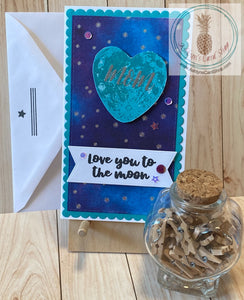 Galaxy themed Mother's Day card with a heart shaped moon popped up on a starry patterned paper background adorned with coordinating sequins. "Mom" is heat embossed on the moon. External sentiment reads "love you to the moon" and the internal sentiment adds a little humour: "thanks for the genes . . . no wonder I'm awesome!" Teal version shown with coordinating envelope. Mini slim card size 3.5 x 6".