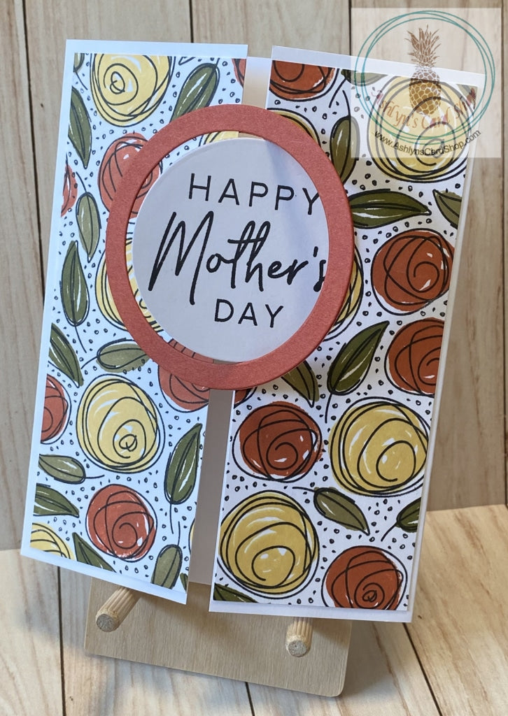 A gatefold Mother's Day card with an interlocking circle and frame on the front. The hand stamped background pattern consists of whimsical roses stamped in yellow and orange and greenery stamped in two shades. External sentiment reads "Happy Mother's Day" and the internal sentiment reads "Words cannot begin to explain how much your love and support has meant to me." Card size is A2 (4.25 x 5.5"). Coordinating envelope included.