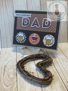 Father's Day card with a barbeque theme. High quality handmade greeting card with hand coloured images that represent Dads. Mounted to a kraft coloured card base, a dark brown die cut frame with inlaid pieces of patterned paper showcases the sentiments and coloured images in this design. Patterned paper varies amongst the versions. A2 Card Size: 4.25 x 5.5". Coordinating envelope included. Grill & Beer version.