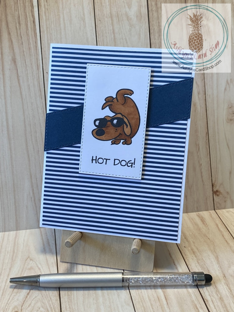 A cool sunglass-wearing dog dude doing a handstand is handcoloured on a white stitched rectangle die cut which is popped up over a diagonal card stock strip that coordinates with the striped coloured patterned paper background. Attached to a white card base. External sentiment reads "hot dog!"; internal sentiment reads "and the award for best parent goes to . . . you. Thanks, Dad". A2 card size: 4.25 x 5.5".  Coordinating envelope included. Navy blue version.
