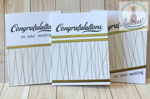 High quality handmade wedding cards featuring simple gold and white designs with  sentiments stamped in black. Decorative tape and foil tape in gold mounted on a white card base.  Sentiments read "Congratulations on your wedding". A2 card size: 4.25 x 5.5".  Coordinating envelope included. Single, double and triple stripe versions shown.