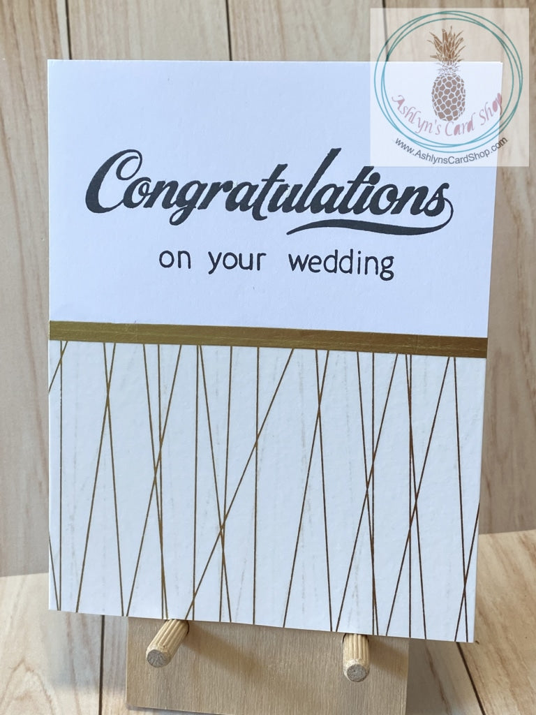 High quality handmade wedding cards featuring simple gold and white designs with  sentiments stamped in black. Decorative tape and foil tape in gold mounted on a white card base.  Sentiments read "Congratulations on your wedding". A2 card size: 4.25 x 5.5".  Coordinating envelope included. Single stripe version.