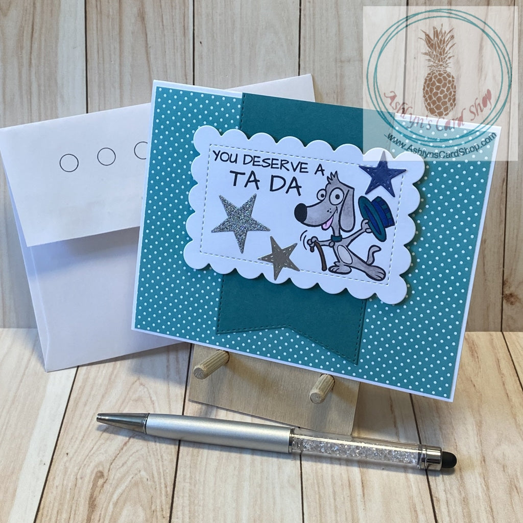 A cute magical puppy says your dad deserves a Ta Da! Hand coloured cartoon dog with a hat and cane stamped on a white scalloped rectangle that is popped up over a large banner (with stitched detail) in a colour that coordinates with the polka dot patterned paper background. External sentiment reads "you deserve a TA DA"; internal sentiment reads "Dad, thanks for everything that you do". A2 card size: 4.25 x 5.5". Coordinating envelope (shown) included. Teal version.