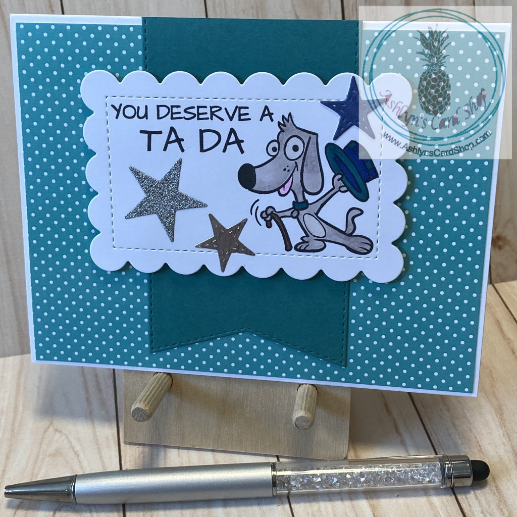 A cute magical puppy says your dad deserves a Ta Da! Hand coloured cartoon dog with a hat and cane stamped on a white scalloped rectangle that is popped up over a large banner (with stitched detail) in a colour that coordinates with the polka dot patterned paper background. External sentiment reads "you deserve a TA DA"; internal sentiment reads "Dad, thanks for everything that you do". A2 card size: 4.25 x 5.5". Coordinating envelope included. Teal version.
