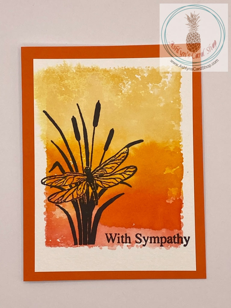 Sympathy card with a watercolour wash background stamped with a dragonfly (on orange) in silhouette. The sentiments read: with sympathy (external) and may your heart find comfort (internal). A2 sized card: 4.25 x 5.5". Coordinating envelope included.